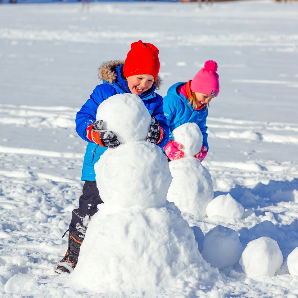Children building snowman in winter Children building snowman in winter