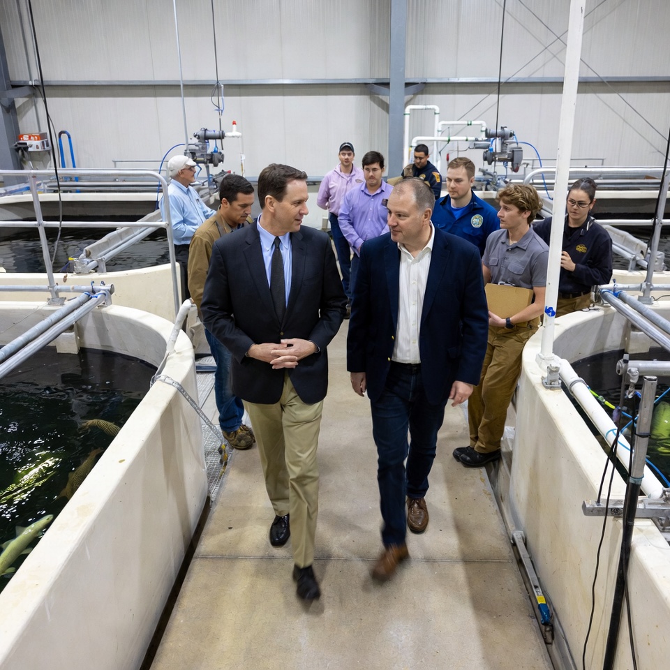 Men touring aquaculture fish tanks facility Men touring aquaculture fish tanks facility