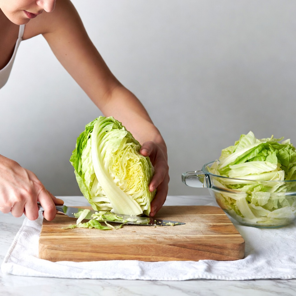 Woman chopping cabbage on cutting board Woman chopping cabbage on cutting board