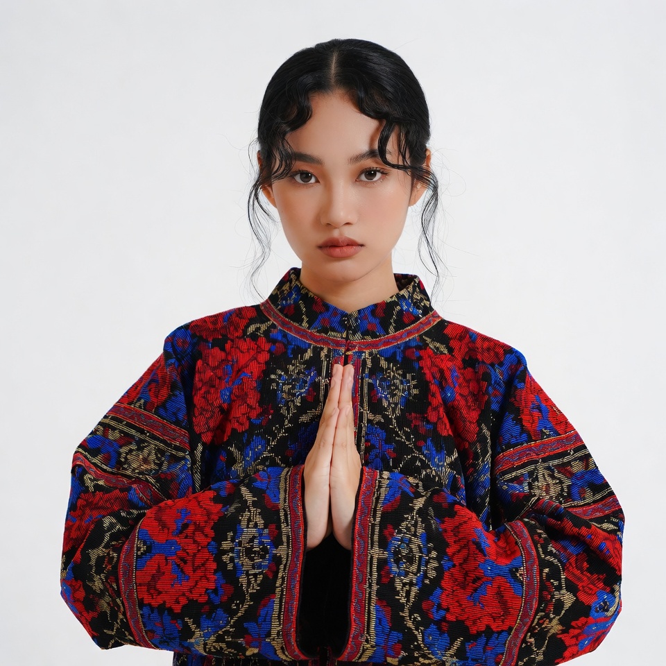 Asian woman in embroidered jacket praying Asian woman in embroidered jacket praying