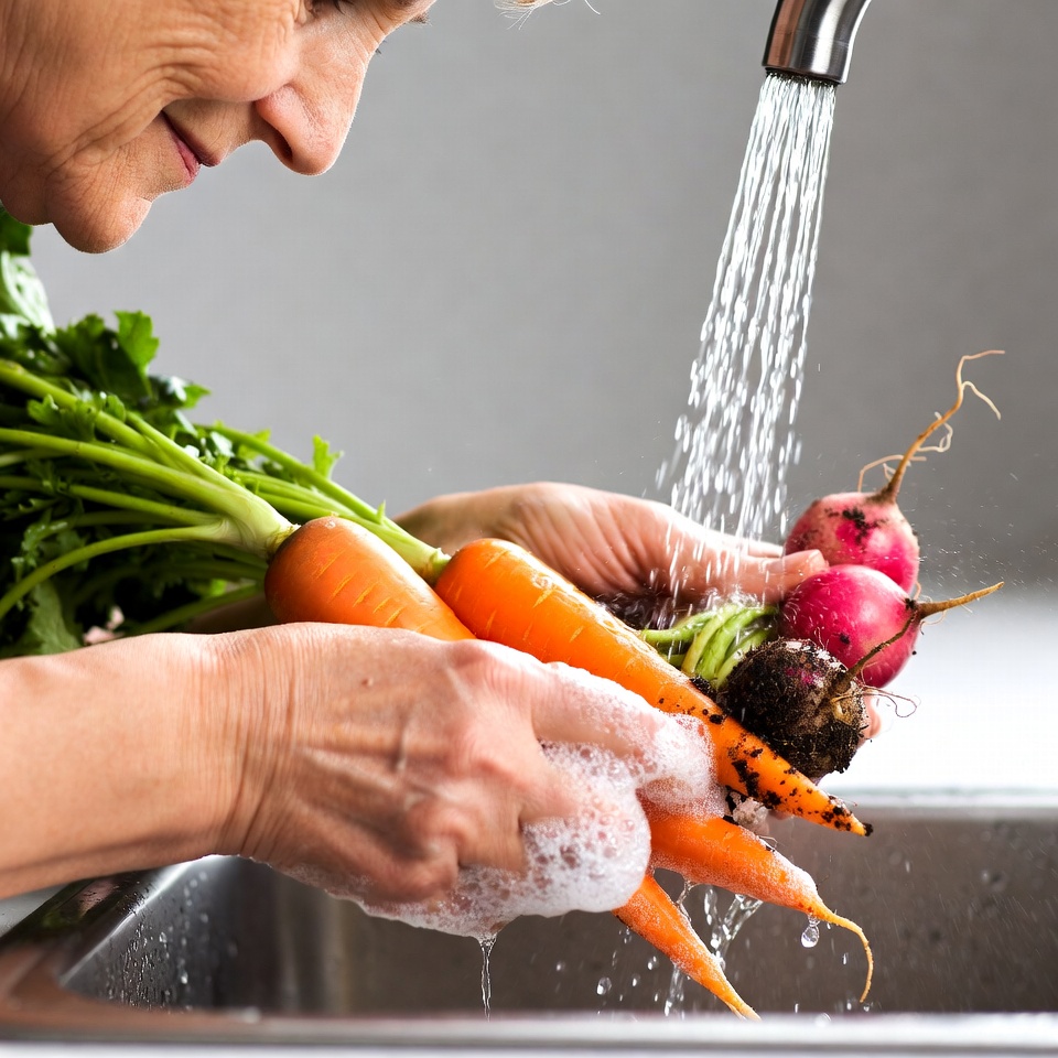 Elderly woman washing carrots sink Elderly woman washing carrots sink