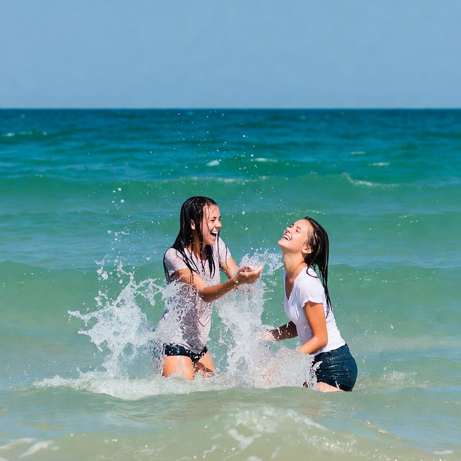 Two girls splashing in ocean water Two girls splashing in ocean water