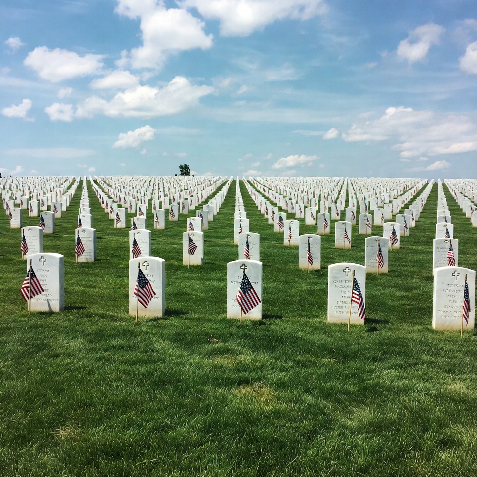 American flags on gravestones in cemetery American flags on gravestones in cemetery