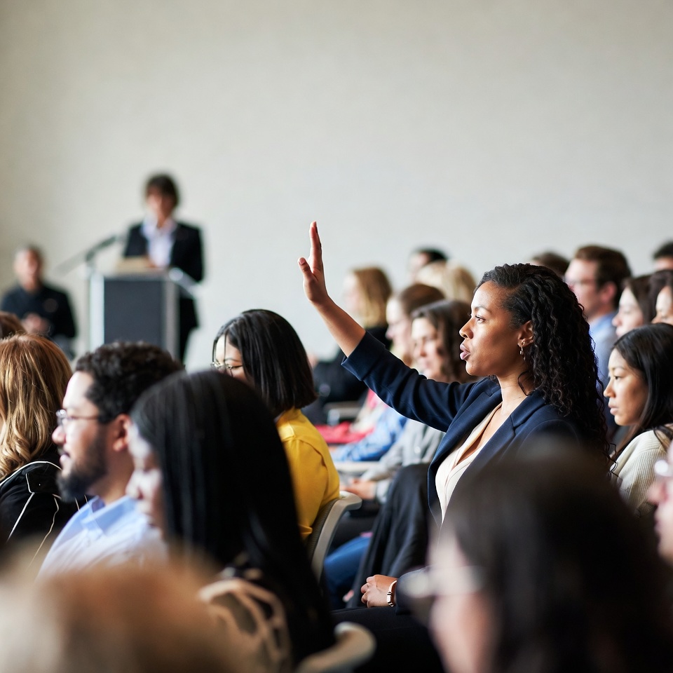 African-American woman raising hand in conference African-American woman raising hand in conference