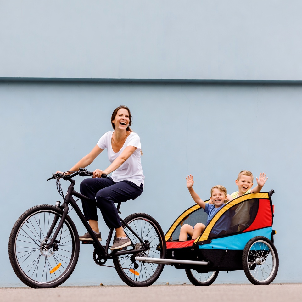 Mother biking with two boys in trailer Mother biking with two boys in trailer