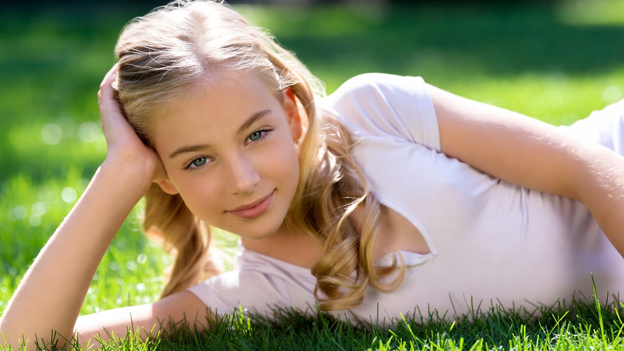 Blonde girl lying on green grass Blonde girl lying on green grass