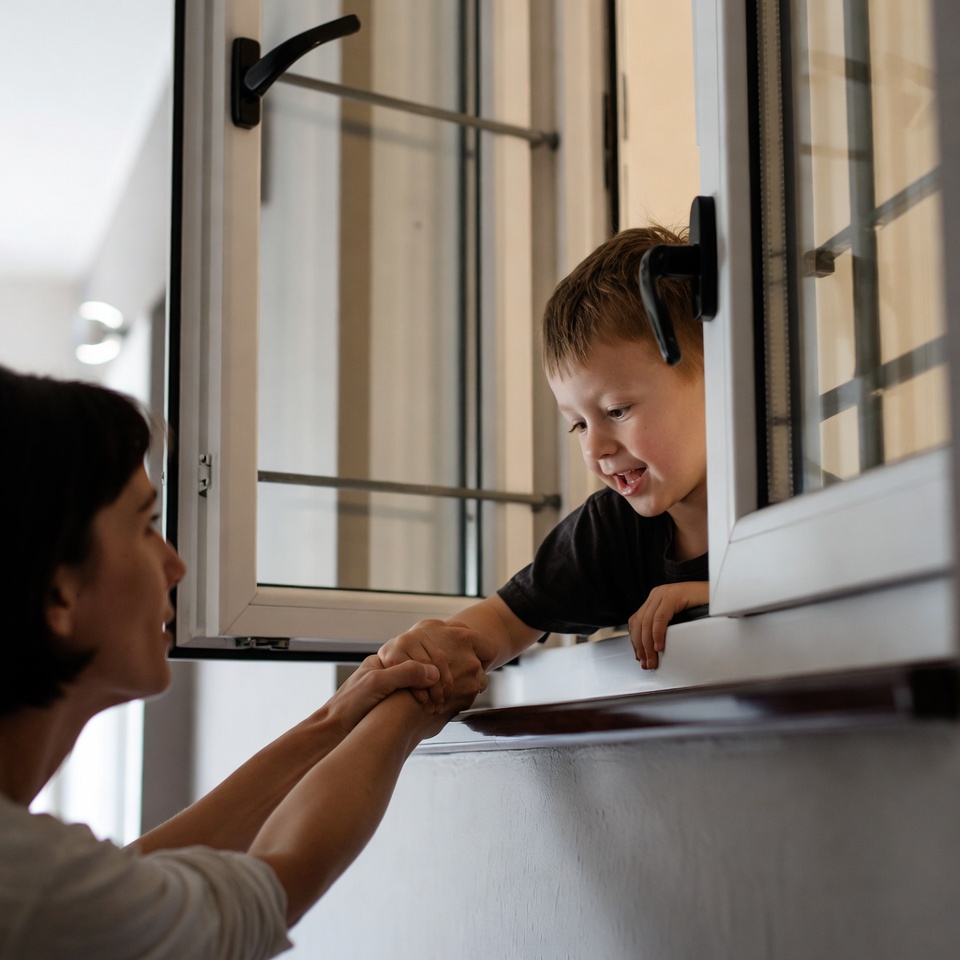 Mother holding toddler's hands at window Mother holding toddler's hands at window