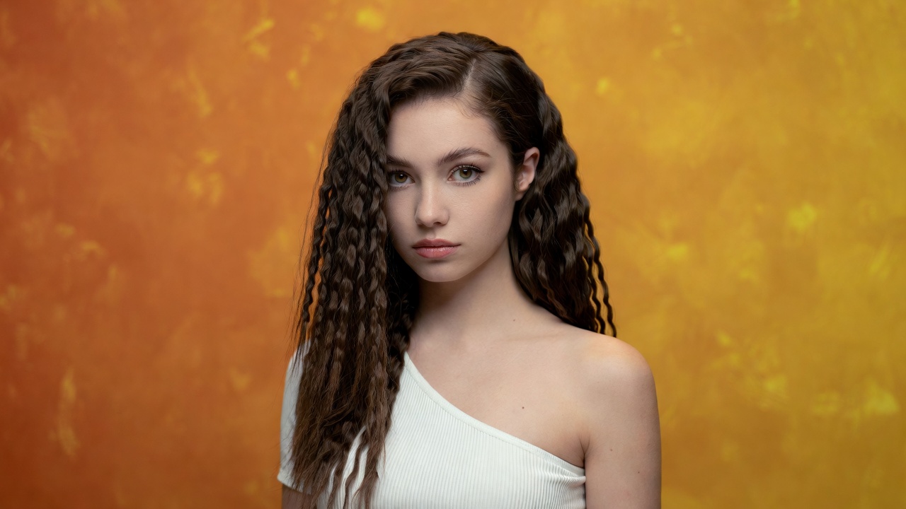 Young woman with curly hair on orange background Young woman with curly hair on orange background