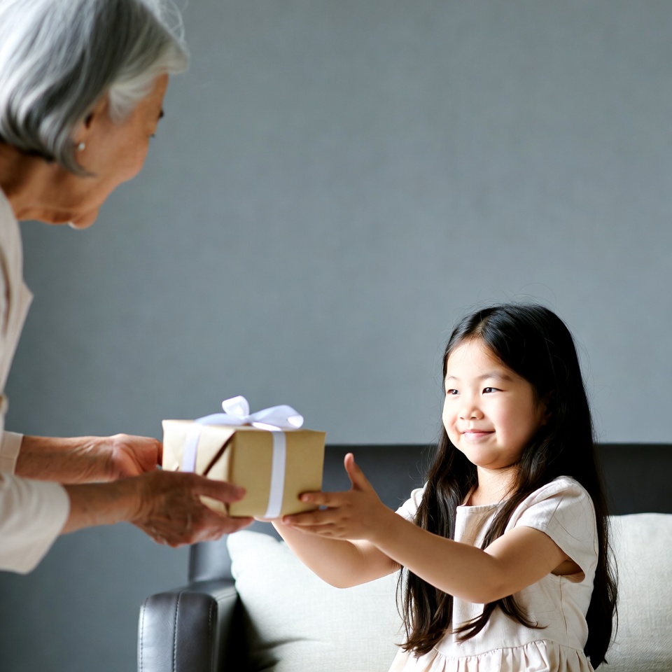 Elderly woman giving gift to Asian girl Elderly woman giving gift to Asian girl