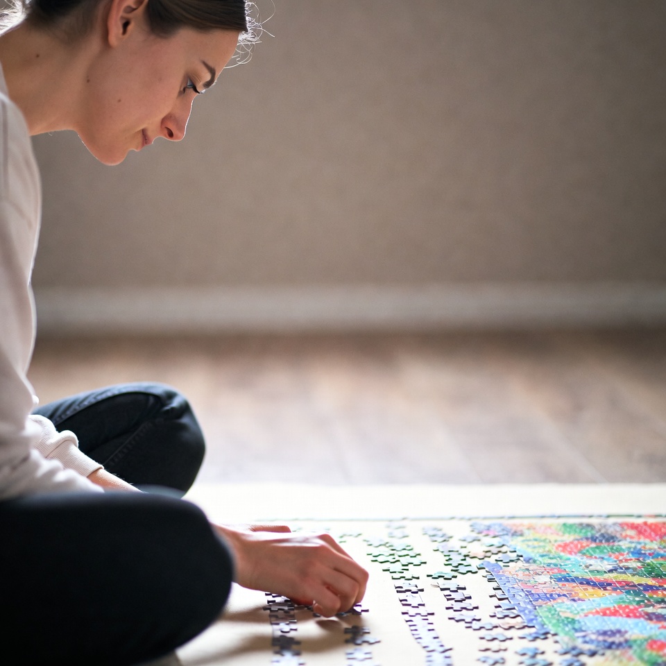 Woman assembling colorful jigsaw puzzle Woman assembling colorful jigsaw puzzle