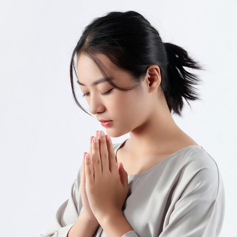 Asian woman praying with hands clasped Asian woman praying with hands clasped