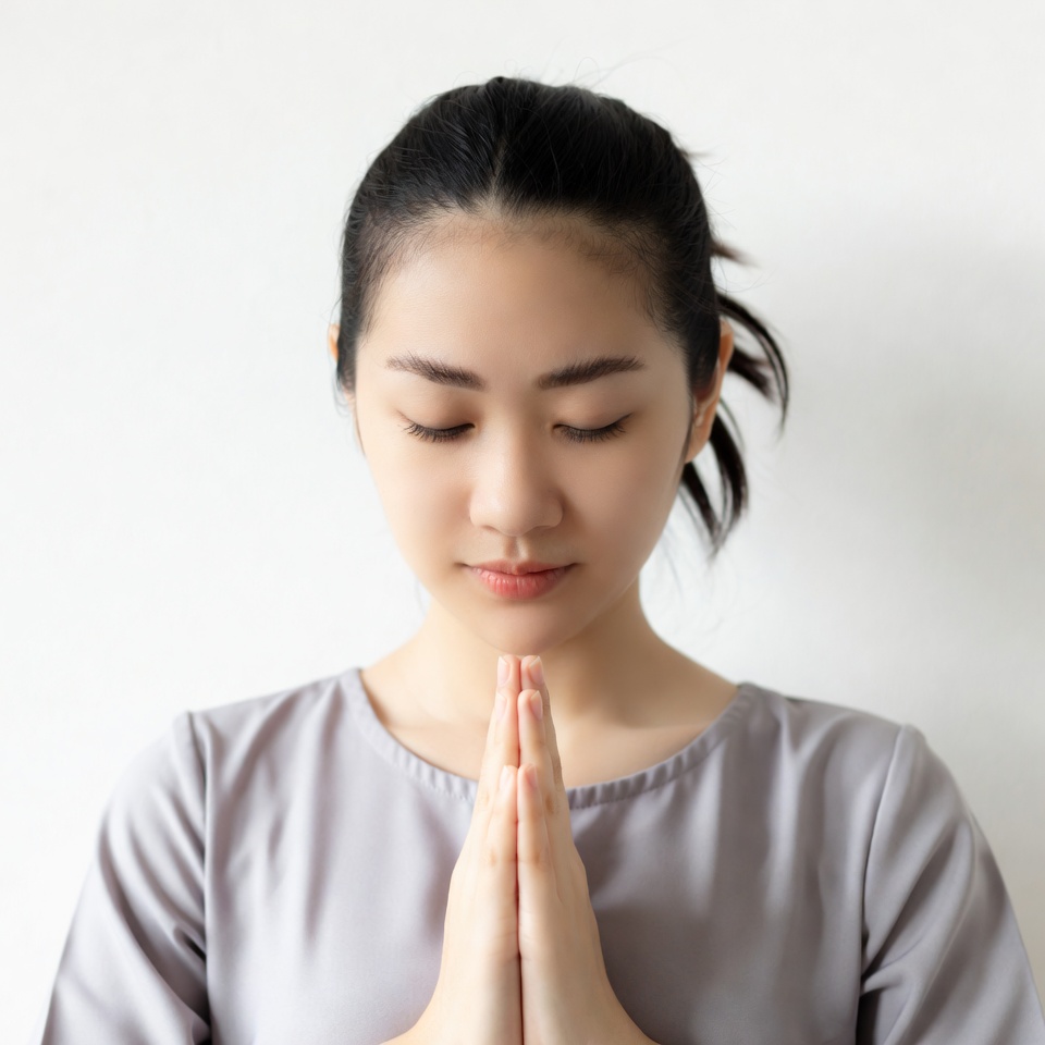 Asian woman praying with hands clasped Asian woman praying with hands clasped