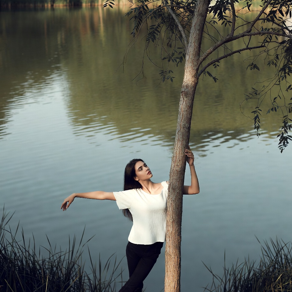 Woman leaning on tree by lake Woman leaning on tree by lake