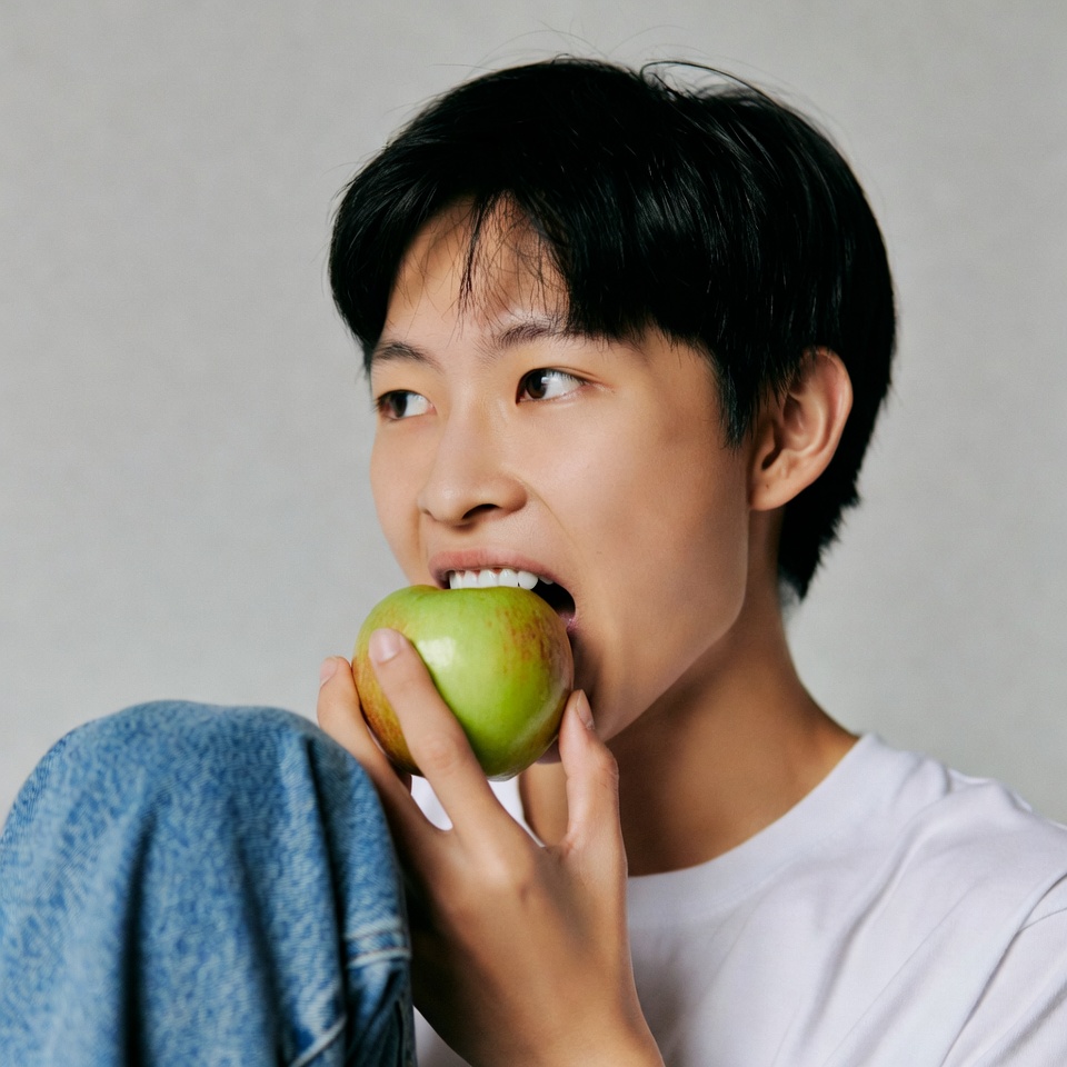 Asian man biting green apple Asian man biting green apple