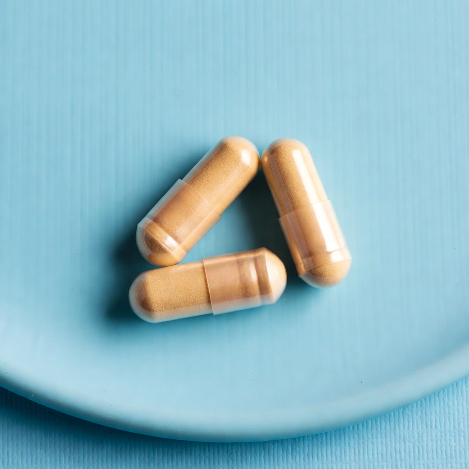 Three Orange Capsules on Blue Plate Three Orange Capsules on Blue Plate