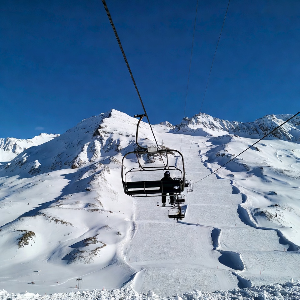 Skier on chairlift over snowy mountains Skier on chairlift over snowy mountains
