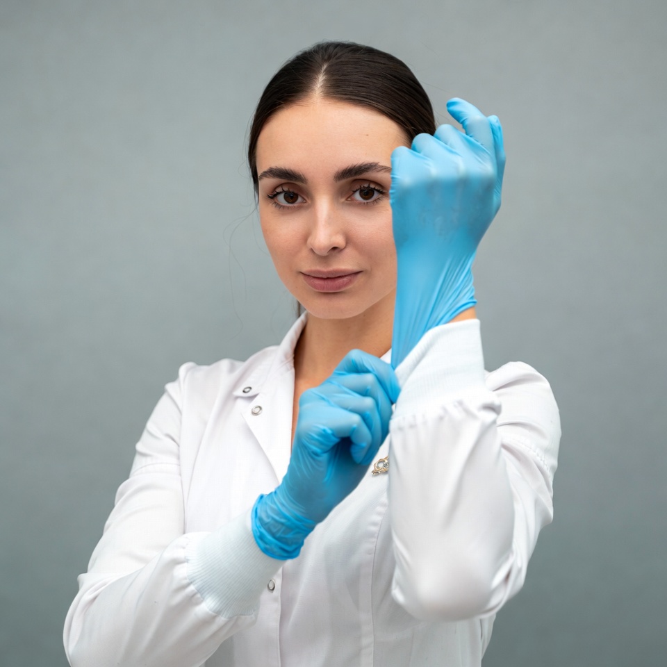 Woman putting on blue gloves Woman putting on blue gloves