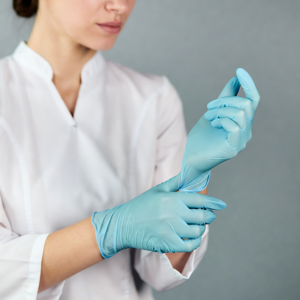 Woman putting on blue gloves Woman putting on blue gloves