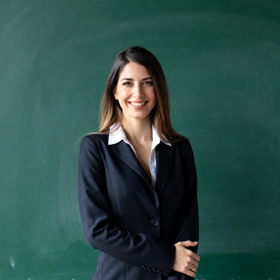 Smiling woman in suit by green chalkboard Smiling woman in suit by green chalkboard