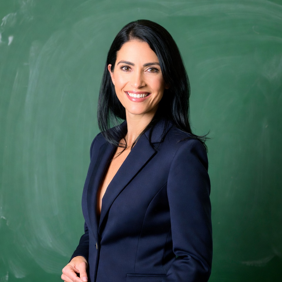 Smiling woman in navy blazer by green chalkboard Smiling woman in navy blazer by green chalkboard
