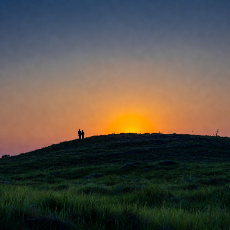 Silhouette couple watching sunset on hill Silhouette couple watching sunset on hill