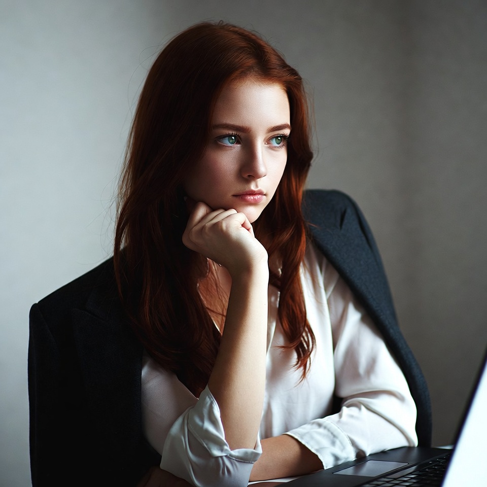 Redhead woman thinking at laptop Redhead woman thinking at laptop