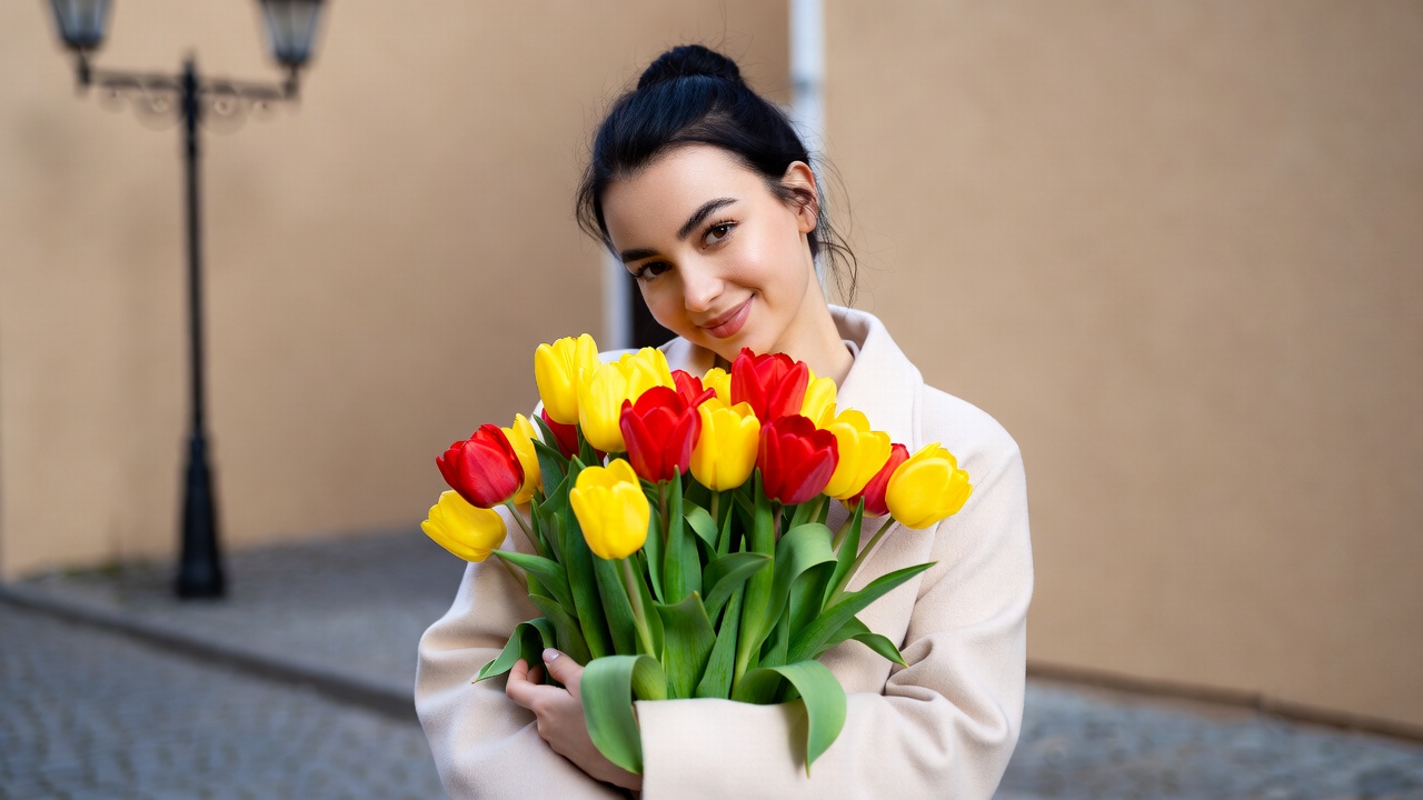 Woman holding yellow red tulips Woman holding yellow red tulips