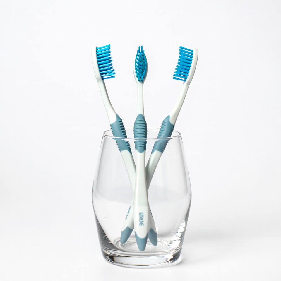 Three blue toothbrushes in glass Three blue toothbrushes in glass