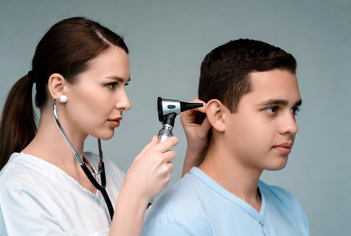 Doctor examining boy's ear with otoscope Doctor examining boy's ear with otoscope
