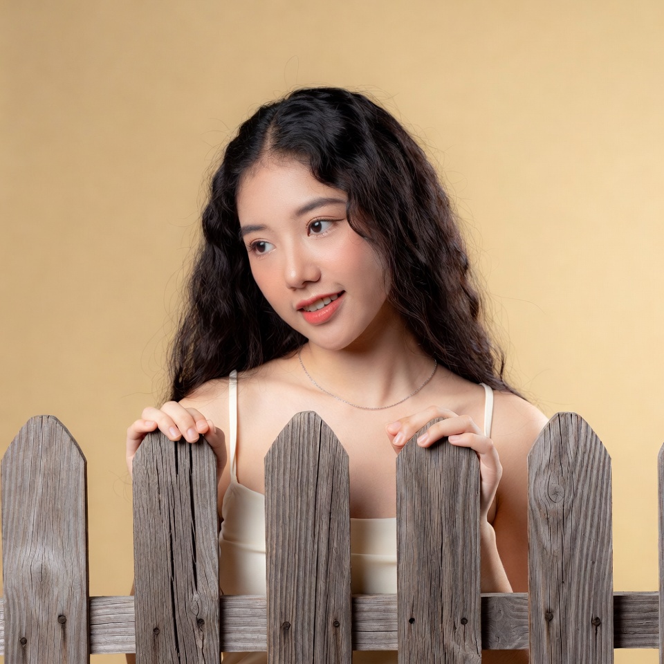 Asian woman peeking over wooden fence Asian woman peeking over wooden fence