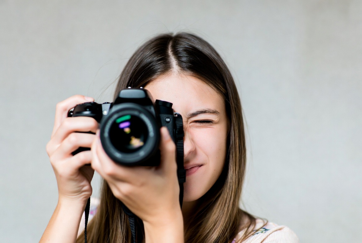 Young woman looking through camera Young woman looking through camera