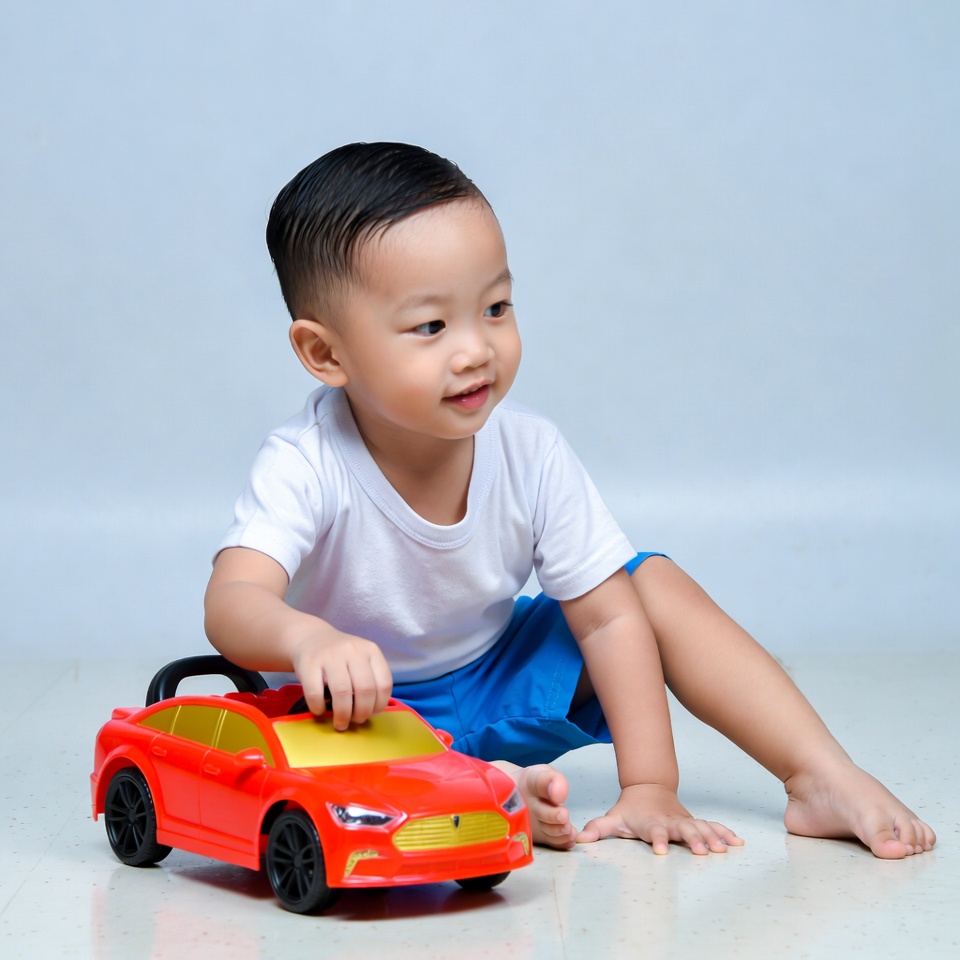 Asian toddler playing with red toy car Asian toddler playing with red toy car