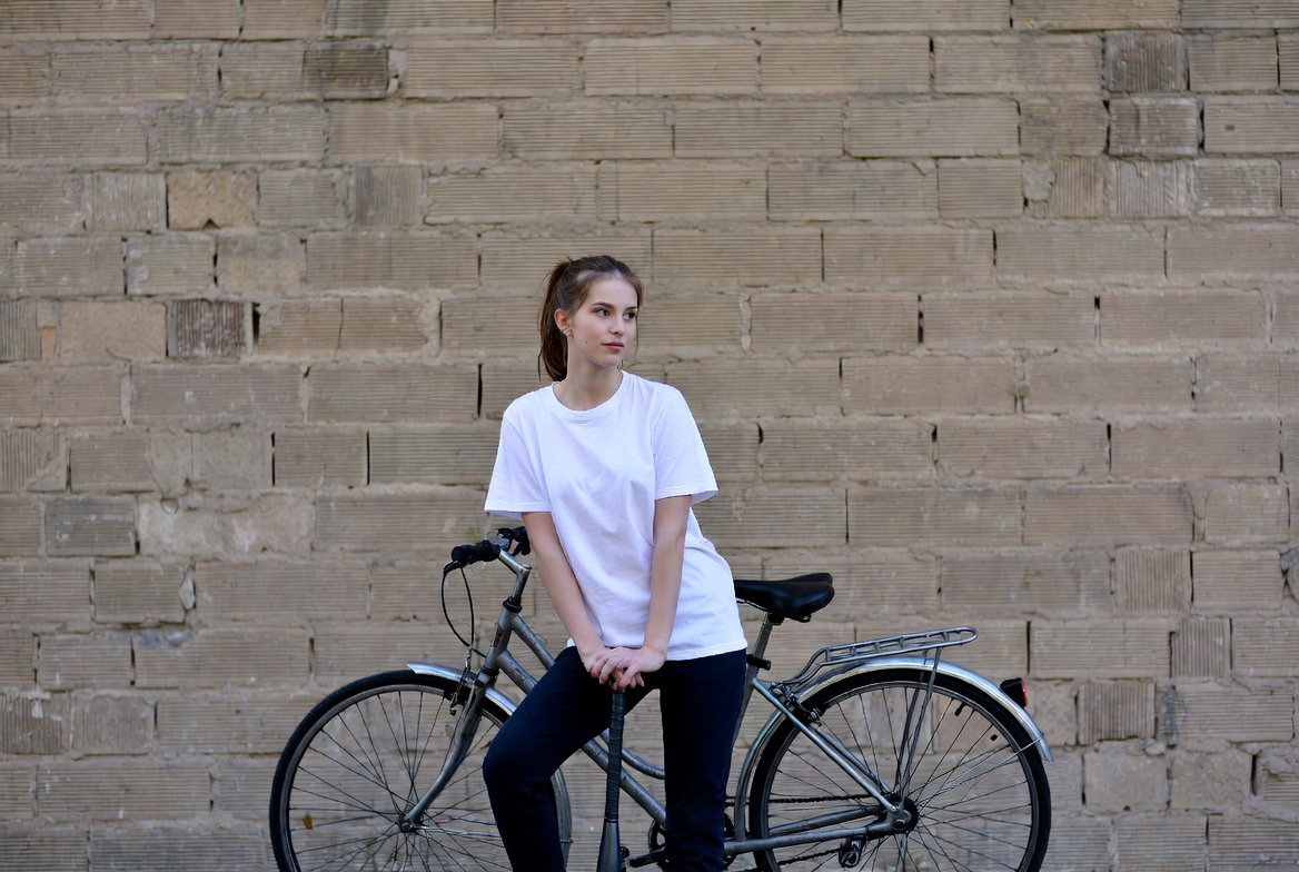 Woman leaning on bicycle against brick wall Woman leaning on bicycle against brick wall