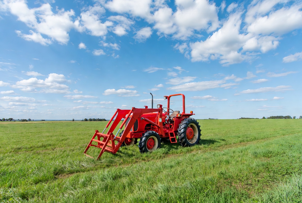Red loader tractor in green field Red loader tractor in green field