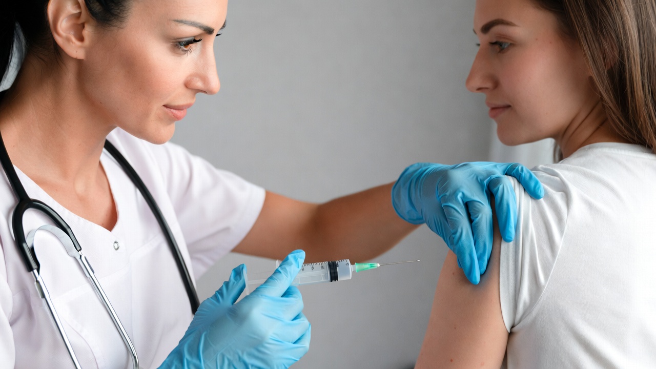 Nurse administering vaccine to woman Nurse administering vaccine to woman