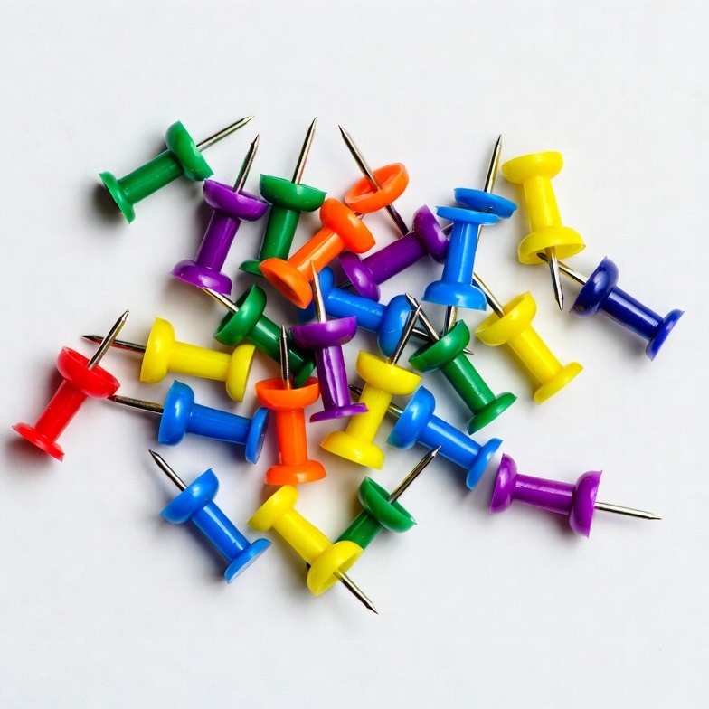 Colorful push pins scattered on white Colorful push pins scattered on white