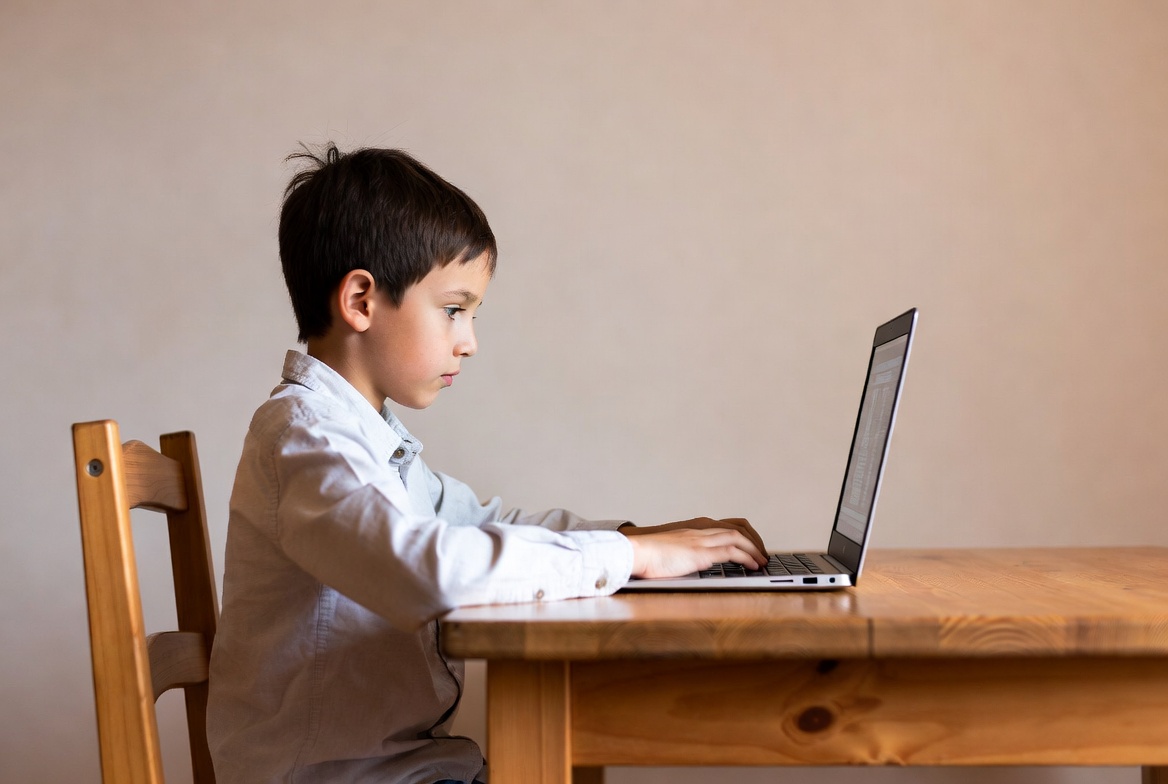 Boy using laptop at wooden desk Boy using laptop at wooden desk