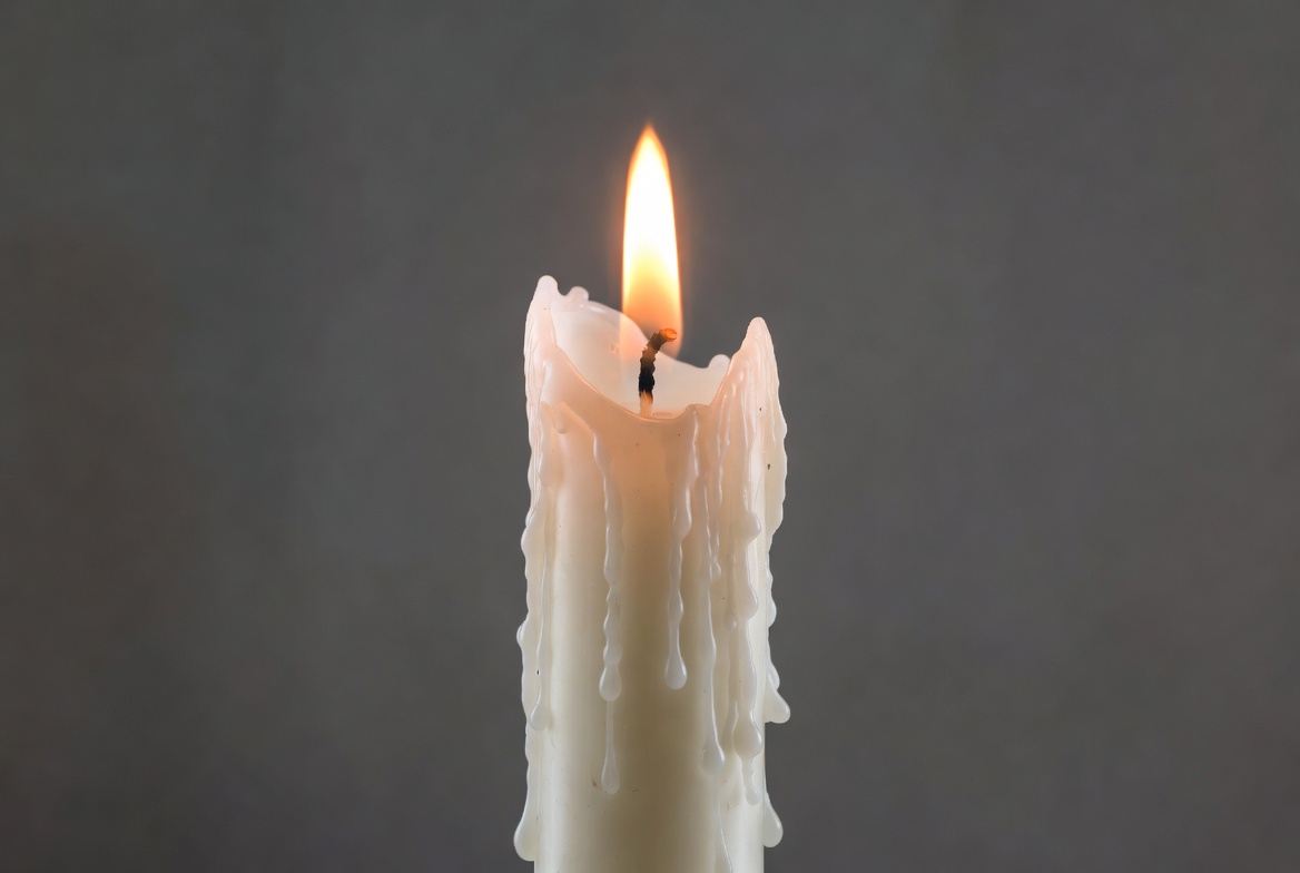 Burning white candle with dripping wax Burning white candle with dripping wax
