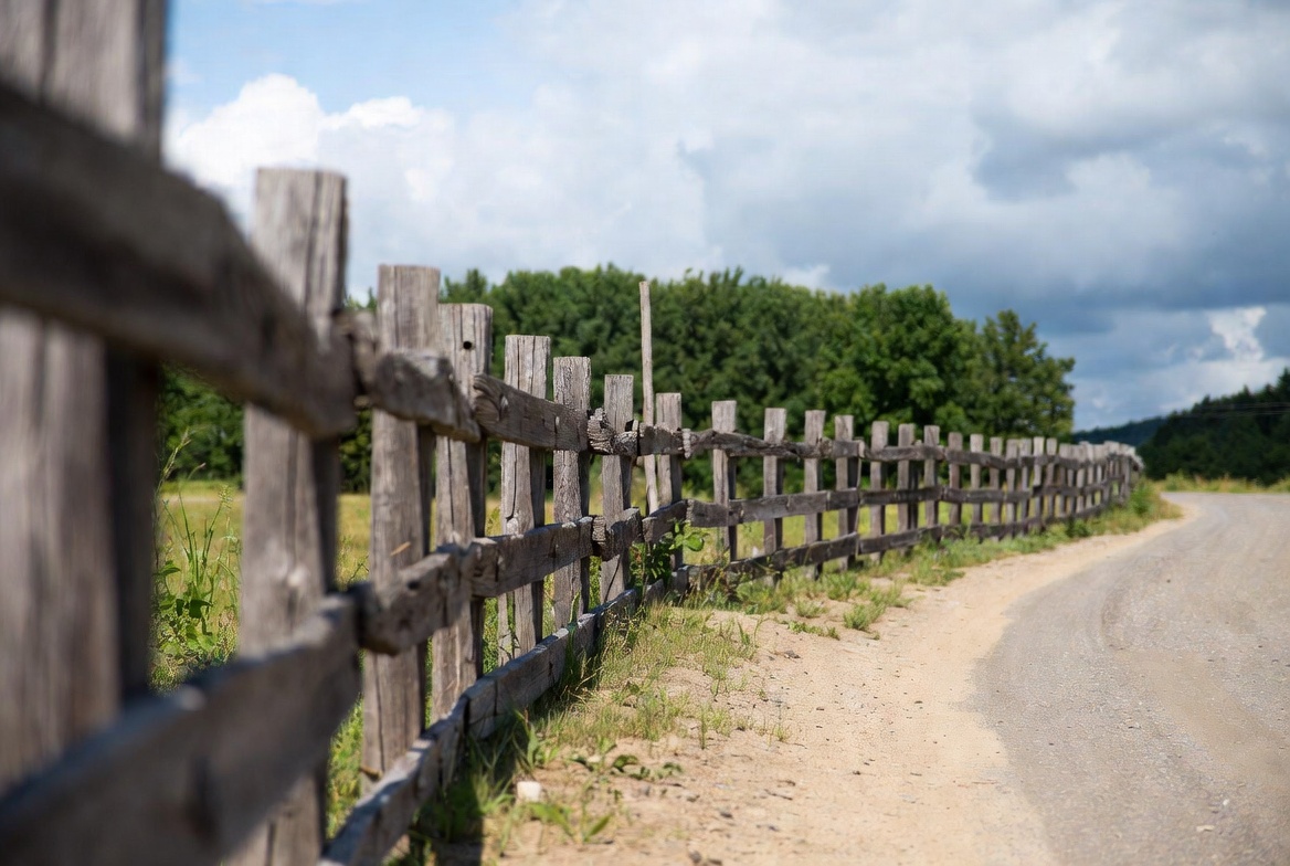Wooden fence along rural dirt road Wooden fence along rural dirt road