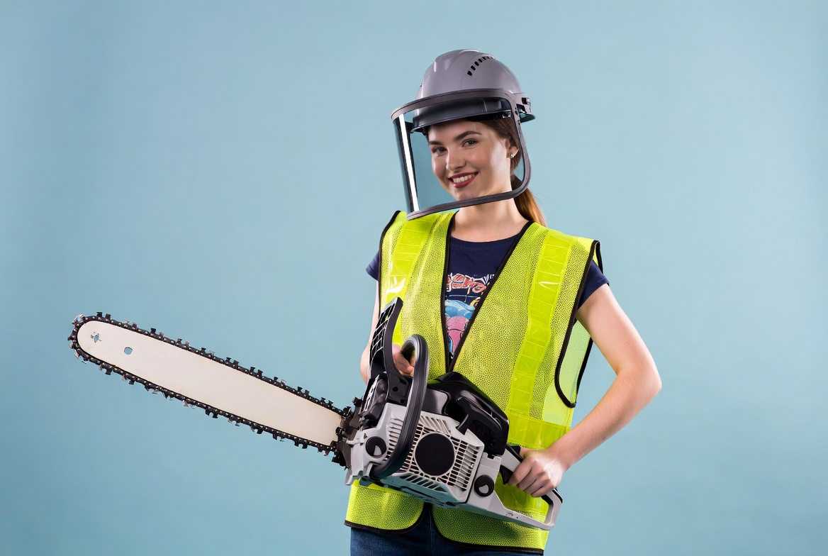 Woman holding chainsaw in safety gear Woman holding chainsaw in safety gear