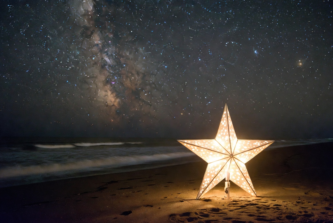 Girl beside glowing star lantern on beach Girl beside glowing star lantern on beach