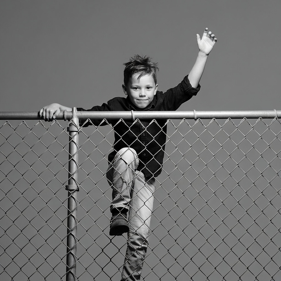 Boy climbing chain link fence Boy climbing chain link fence