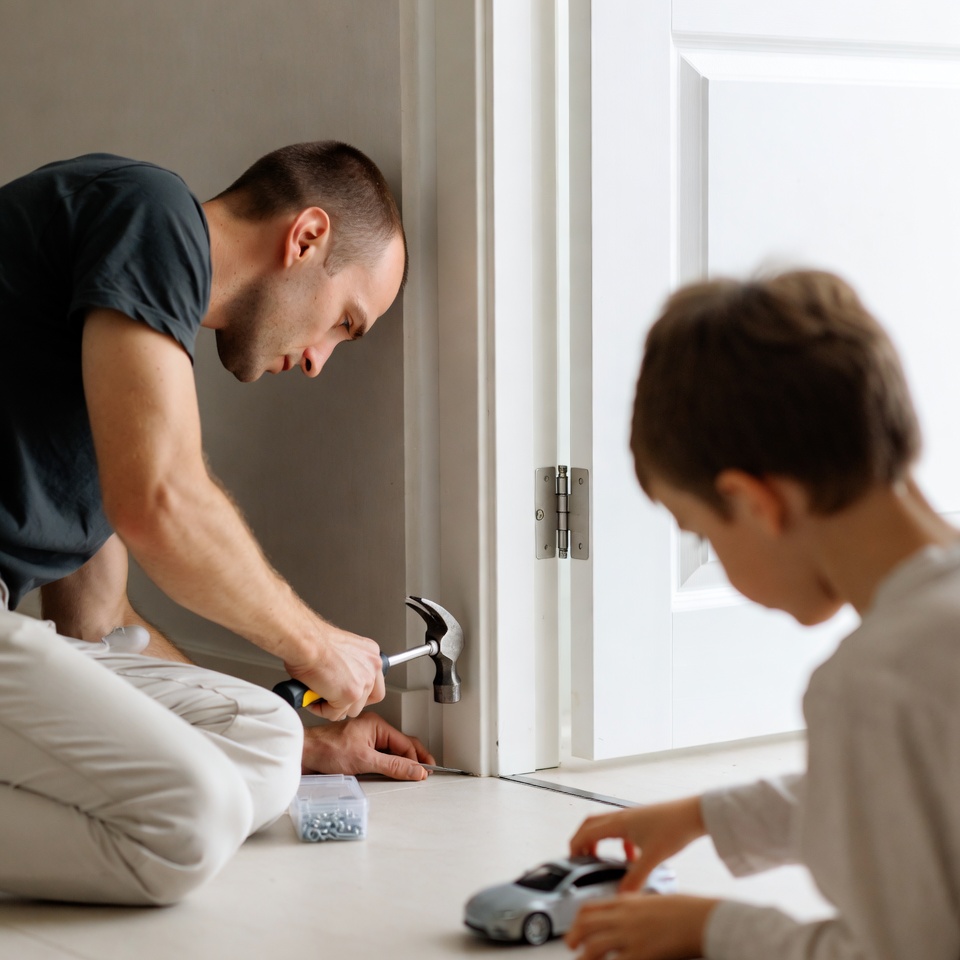 Father and son installing door hinge Father and son installing door hinge