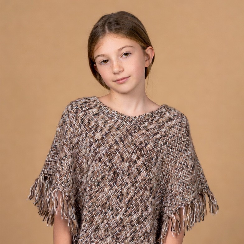 Girl wearing fringed knit poncho Girl wearing fringed knit poncho