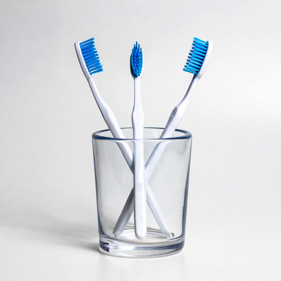 Three Blue Toothbrushes in Glass Three Blue Toothbrushes in Glass