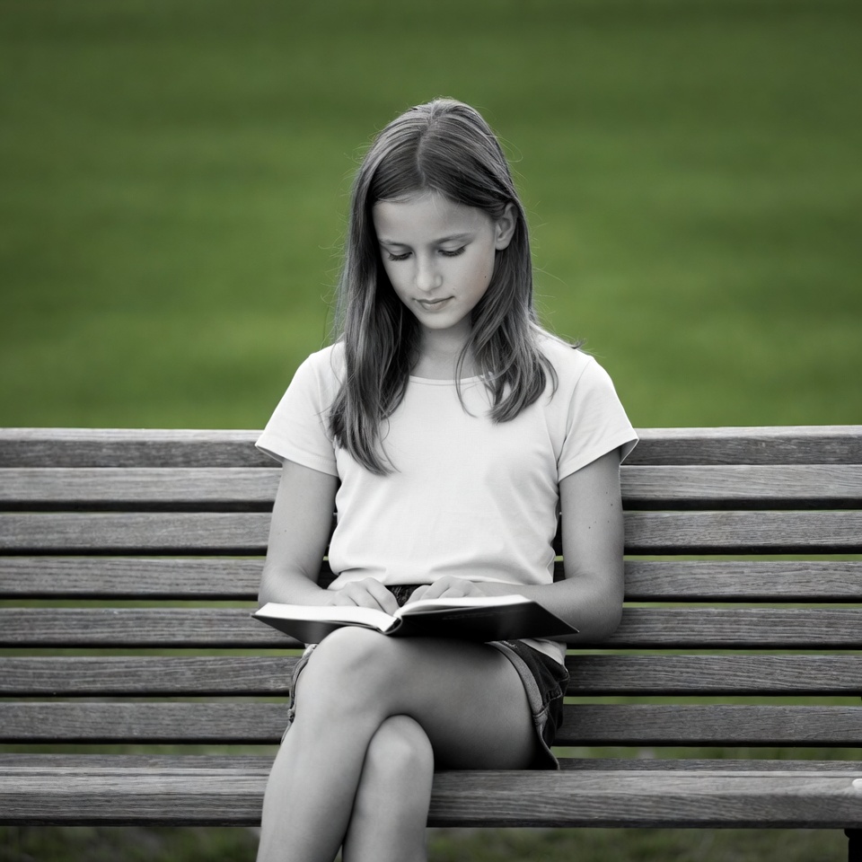 Girl reading book on park bench Girl reading book on park bench