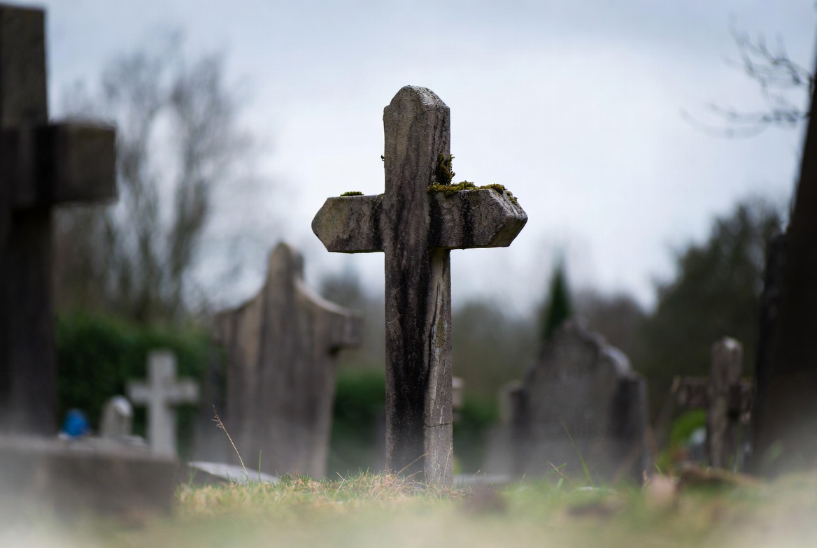 Mossy wooden cross in foggy cemetery Mossy wooden cross in foggy cemetery