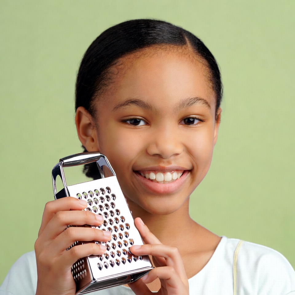 African-American girl holding cheese grater African-American girl holding cheese grater