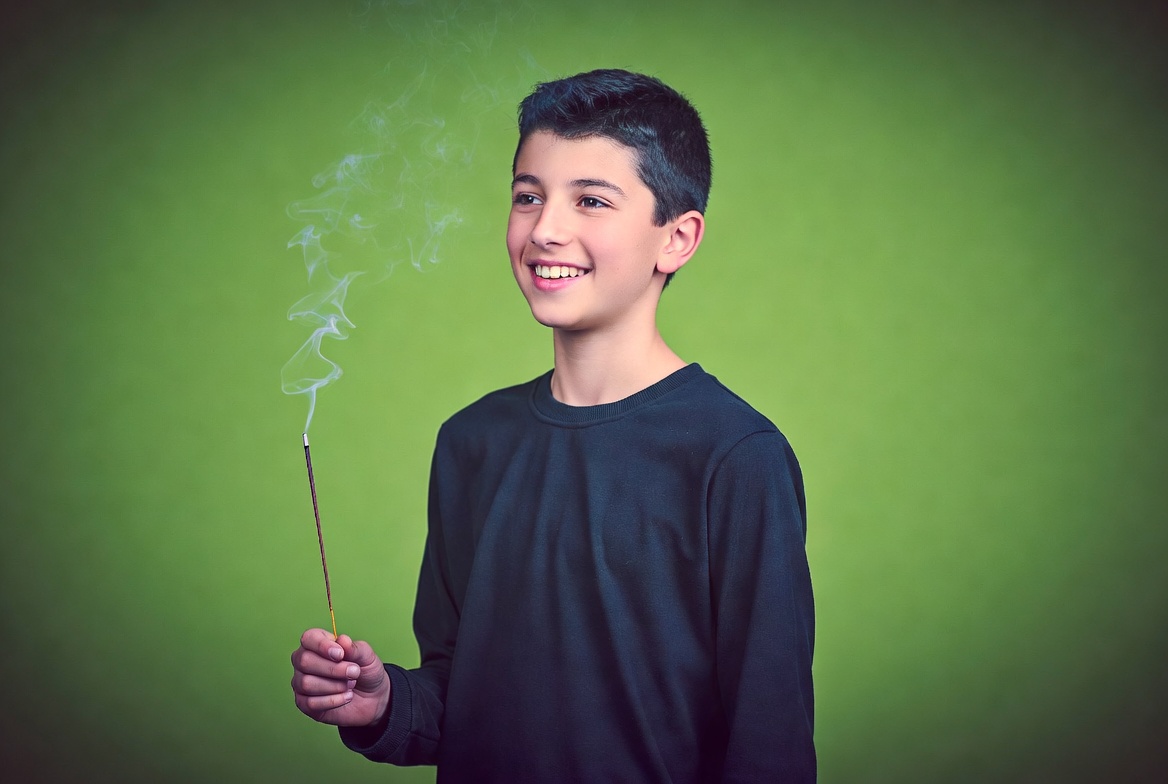 Boy holding lit incense stick Boy holding lit incense stick