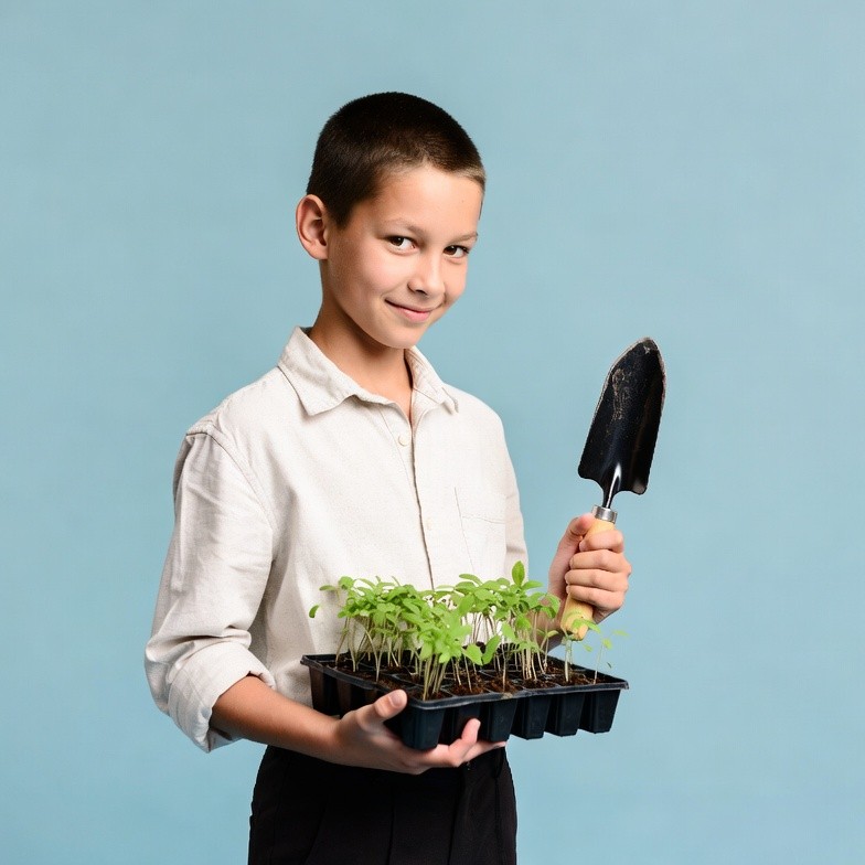 Boy holding seedlings with trowel Boy holding seedlings with trowel